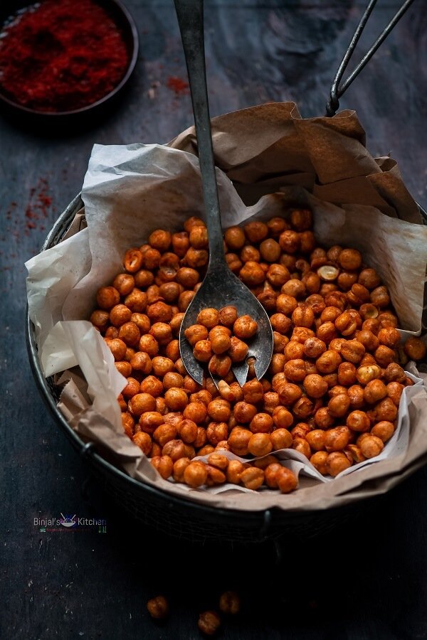 A bowl filled with roasted chickpeas and a spoon.